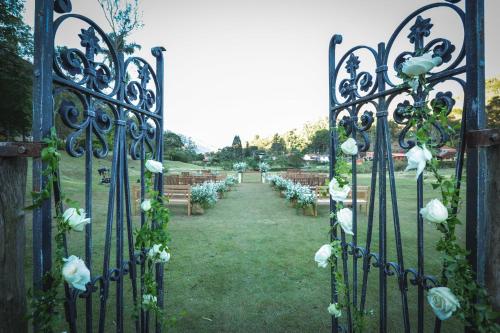 a gate with white roses on it with a row of chairs at Pousada Les Roches in Itaipava
