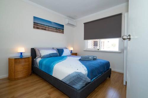 um quarto com uma cama com um edredão azul e uma janela em 24 Burswood Comfort Short Walk To Crown & Optus! - Superhog verification Required em Perth