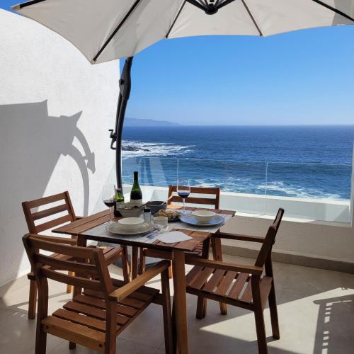 a table and chairs with an umbrella and the ocean at Descanso frente al mar in Viña del Mar