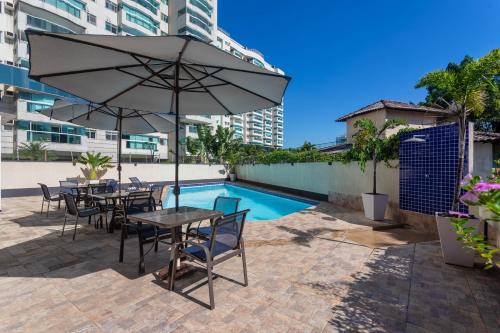 a table and chairs with an umbrella next to a pool at DOM Barra Hotel in Rio de Janeiro