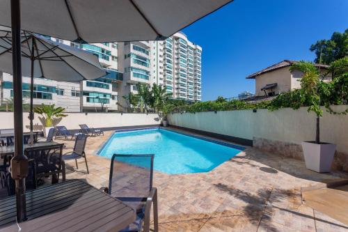 a swimming pool with a table and chairs and an umbrella at TRYP by Wyndham Rio de Janeiro Barra Parque Olímpico in Rio de Janeiro