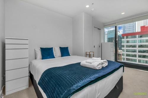 a bedroom with a bed with blue sheets and a window at QV Comfortable Downtown Apartment - 1136 in Auckland