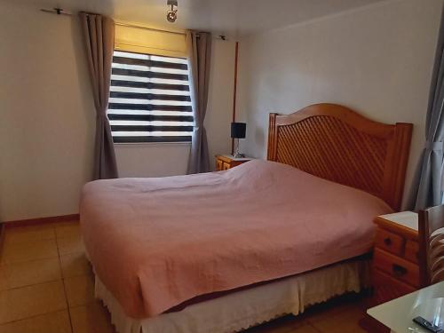 um quarto com uma cama e uma janela em Acogedora casa en Punta Arenas em Punta Arenas