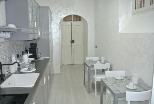 eine weiße Küche mit 2 Tischen und einer weißen Tür in der Unterkunft B&B Insula Urbis in Rom