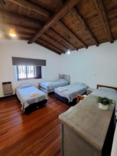 Habitación con 3 camas y suelo de madera. en Casona de coria en Luján de Cuyo