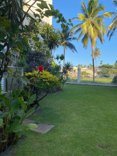 um quintal com relva verde e palmeiras e uma cerca em Praia em Lauro de Freitas