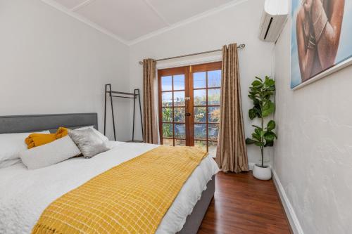 a bedroom with a bed with a yellow blanket at Stylish Lake Albert Cottage, Wagga Wagga in Wagga Wagga
