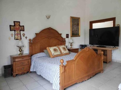 a bedroom with a large wooden bed and a flat screen tv at Las Linas in Tequisquiapan