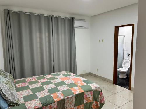 a bedroom with a bed and a bathroom with a toilet at Ap barato e perfeito insta thiagojacomo in Goiânia