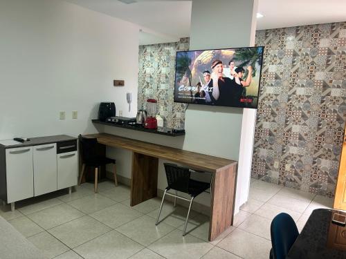 a kitchen with a desk and a tv on a wall at Ap barato e perfeito insta thiagojacomo in Goiânia