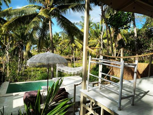 a patio with a chair and an umbrella and a pool at Exotic Private Glamping in Nusa Penida