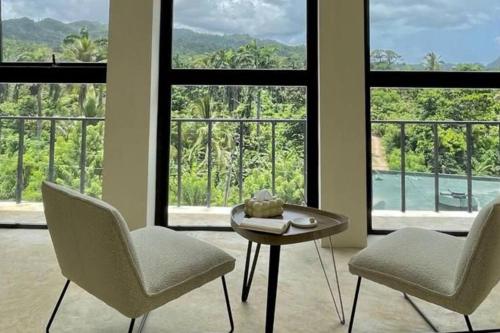 2 Stühle und ein Tisch in einem Zimmer mit Fenstern in der Unterkunft ¡Un Espacio Mágico en El Valle! in Santa Bárbara de Samaná