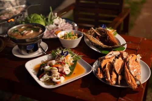 a wooden table with plates of food on it at Janpa Resort in Don Sak