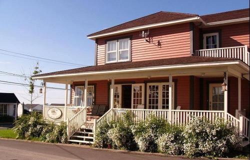 Casa marrón con porche y barandilla blanca en Chez Rose Belaid en Perce