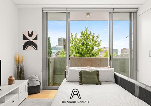 um quarto com uma cama e uma grande janela em Central stylish 1 bedroom with balcony and air-con em Sydney