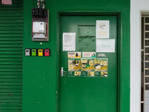 a green door with posters and papers on it at Fadlim Homestay in Padang Serai