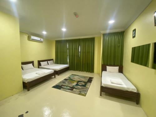 two beds in a room with green curtains at Fadlim Homestay in Padang Serai