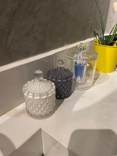 three glass containers sitting on a white shelf at Apto Moderno - Centro in Macapá
