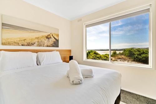 a bedroom with a large white bed with a window at The Blue House in Coles Bay