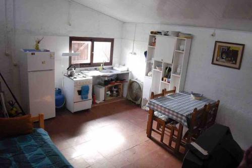 a small kitchen with a table and a refrigerator at Casita en Valizas a 250m del mar in Barra de Valizas