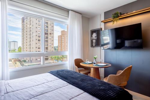a bedroom with a bed and a table and a window at Likehome Connect in Porto Alegre