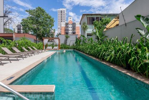 una piscina con sedie a sdraio accanto a un edificio di Likehome Connect a Porto Alegre