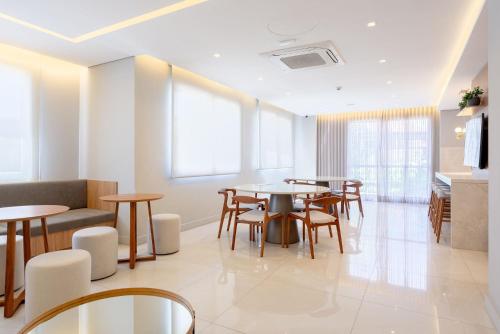 a dining room with tables and chairs and windows at Connect by LikeHome in Porto Alegre