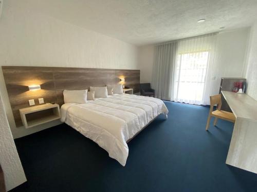 a bedroom with a large white bed with a large window at HOTEL AEROPUERTO MORELIA in Álvaro Obregón