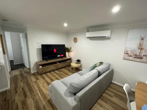 a living room with a couch and a flat screen tv at Central Evans Wagga Apartments in Wagga Wagga