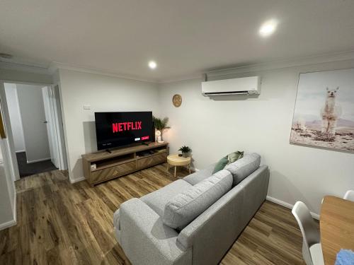 a living room with a couch and a tv at Central Evans Wagga Apartments in Wagga Wagga