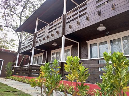 a wooden house with a lot of windows at Satva Cottages in Anjuna