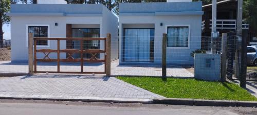 a gate in front of a blue and white house at Morada do bosque in Capão da Canoa