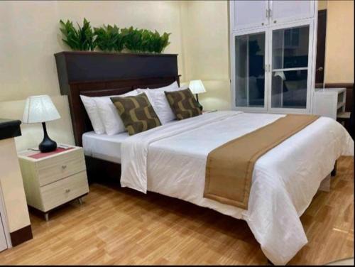 a bedroom with a large white bed with a nightstand and a window at Hillside Hotel in San Jose