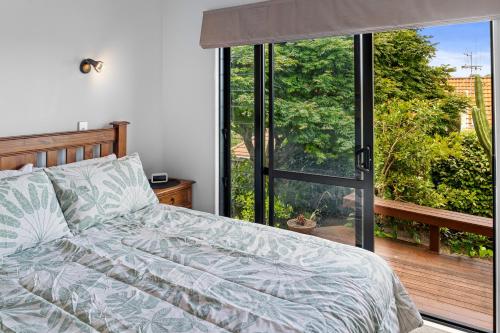 1 dormitorio con cama y ventana grande en Bellevue Paradise - Tauranga Holiday Home, en Tauranga