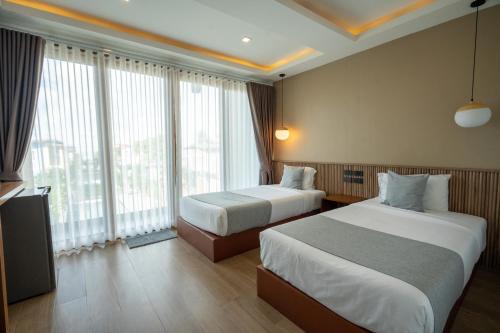 a hotel room with two beds and a large window at Janpa Resort in Don Sak