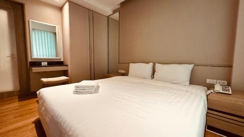 a bedroom with a large white bed with a window at Phu Dahla Apartments in Ban Khlong Haeng