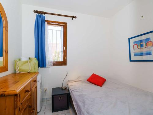 - une chambre avec un lit et une commode avec un oreiller rouge dans l'établissement Appartement T3 avec terrasse, véranda et piscine, à 100m de la mer! Parking, animaux acceptés - FR-1-409-179, à Gruissan