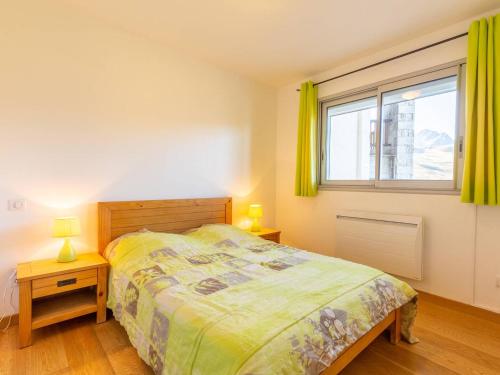 een slaapkamer met een bed en een raam met gele gordijnen bij Appartement Peyragudes, 2 pièces, 6 personnes - FR-1-695-42 in Germ