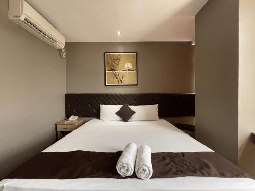 a bedroom with a large white bed with two pairs of towels on it at Cebu Capitol Central Hotel & Suites powered by Cocotel in Cebu City