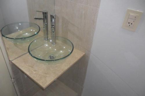 Baño con 2 lavabos de cristal en una encimera en Aparthotel Continental en San Miguel de Tucumán