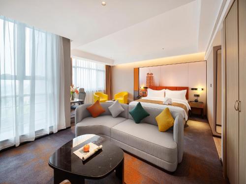 een hotelkamer met een bed en een bank bij Arthur International Hotel - Provincial Science and Technology Museum Xianghu Branch in Zhengzhou