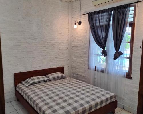 1 dormitorio con 1 cama con manta a cuadros y ventana en Lucia Cottages en Sukarame