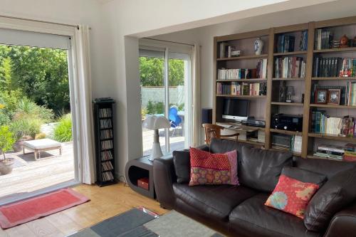 uma sala de estar com um sofá de couro e prateleiras de livros em Sumptuous house with pool em La Rochelle