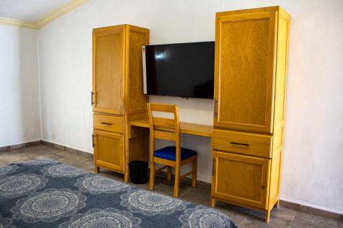 1 dormitorio con escritorio, TV y armario de madera en Hotel Boutique Casa Tellez, 