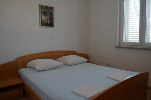 un letto con due cuscini sopra in una camera da letto di Apartments Buljan a Baška