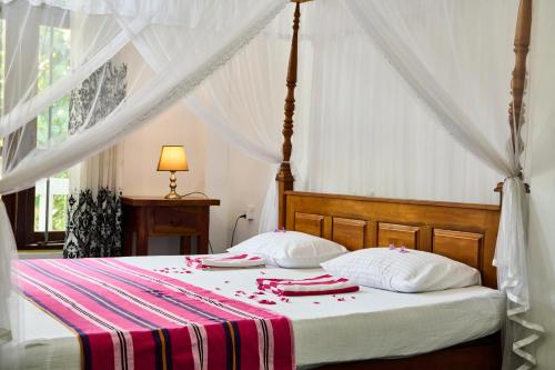 a bedroom with a bed with a red and white blanket at Daasa Guest Mirissa in Mirissa