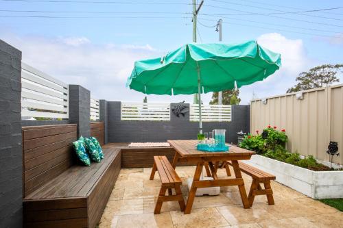 a patio with a wooden table and an umbrella at Villa Zelma I Pet Friendly I 4 Min Walk to Beach in Culburra Beach