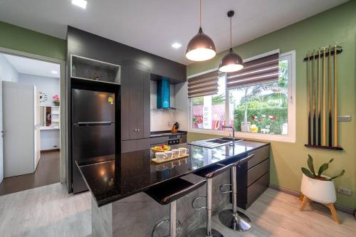 a kitchen with a black counter top and green walls at Luxurious and Playful 5 Bedroom Pool Villa - CC in Na Jomtien