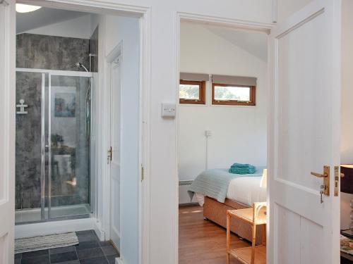 a bedroom with a bed and a glass door with a shower at Flaxpool Well Garden Room in Crowcombe