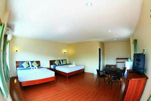 um quarto de hotel com duas camas e uma mesa e cadeiras em Sangkla Resort em Ban Sane Phong